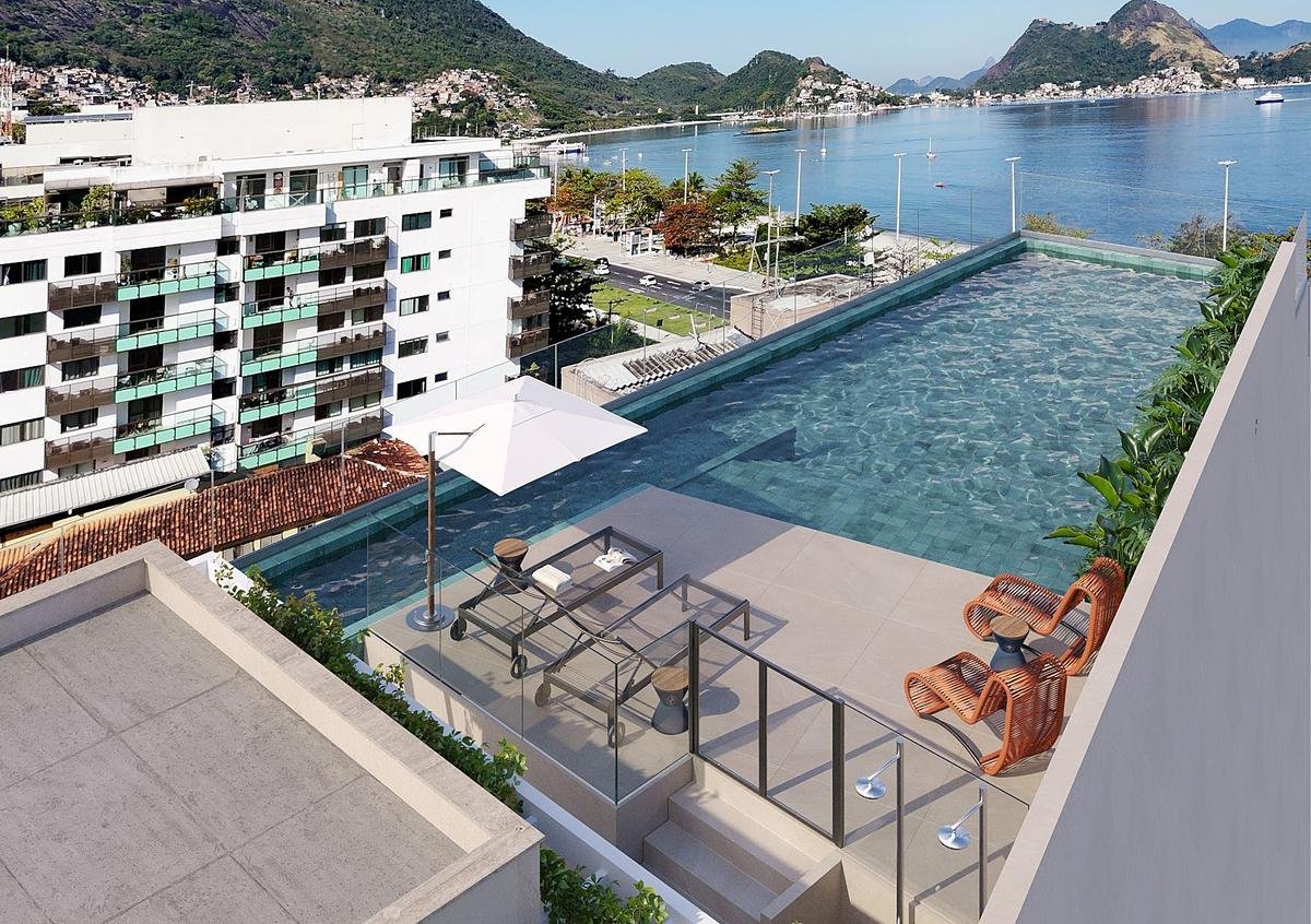 Perspectiva da piscina do rooftop do Sou+ Charitas, com deck e vista para a enseada de Charitas